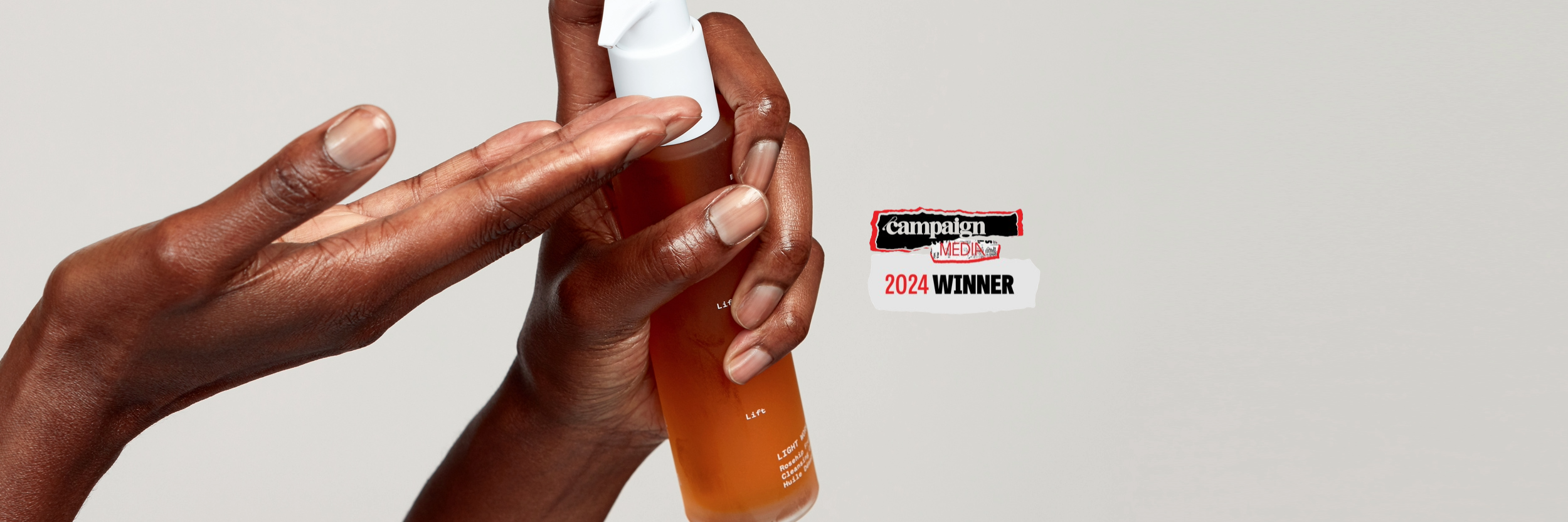 A close up of a woman's hands holding a Pai Skincare rose hip oil product and squirting it into her palm. Accompanied by the Campaign Media Award winners logo.