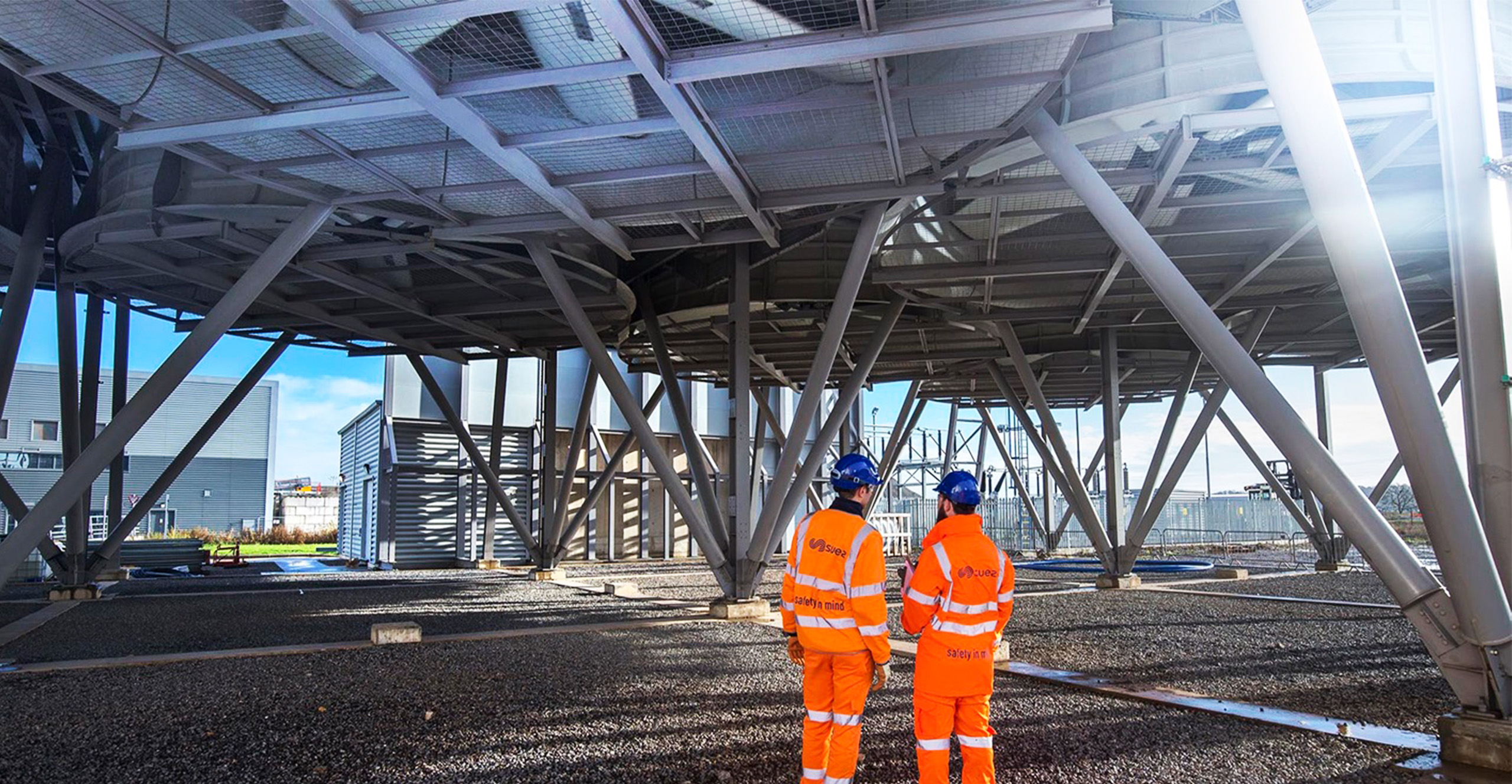 two people dressed in high vis clothing under a metal structure