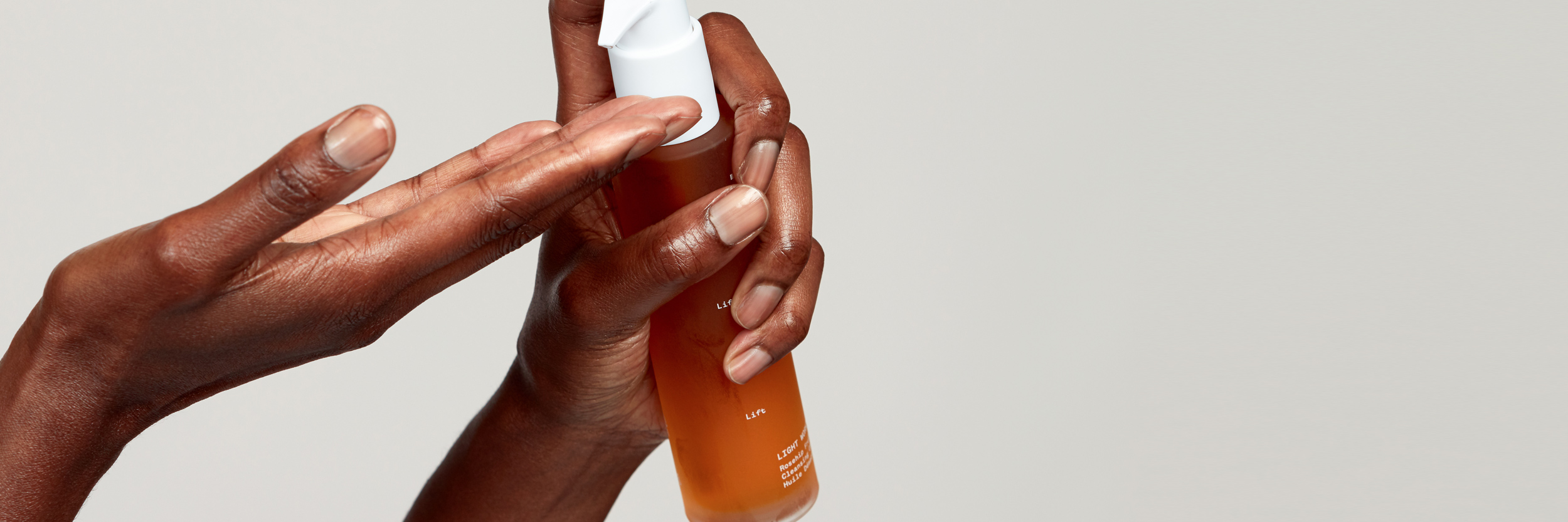 A hand holds a Pai product in an orange bottle and applies the product to the person's other hand.