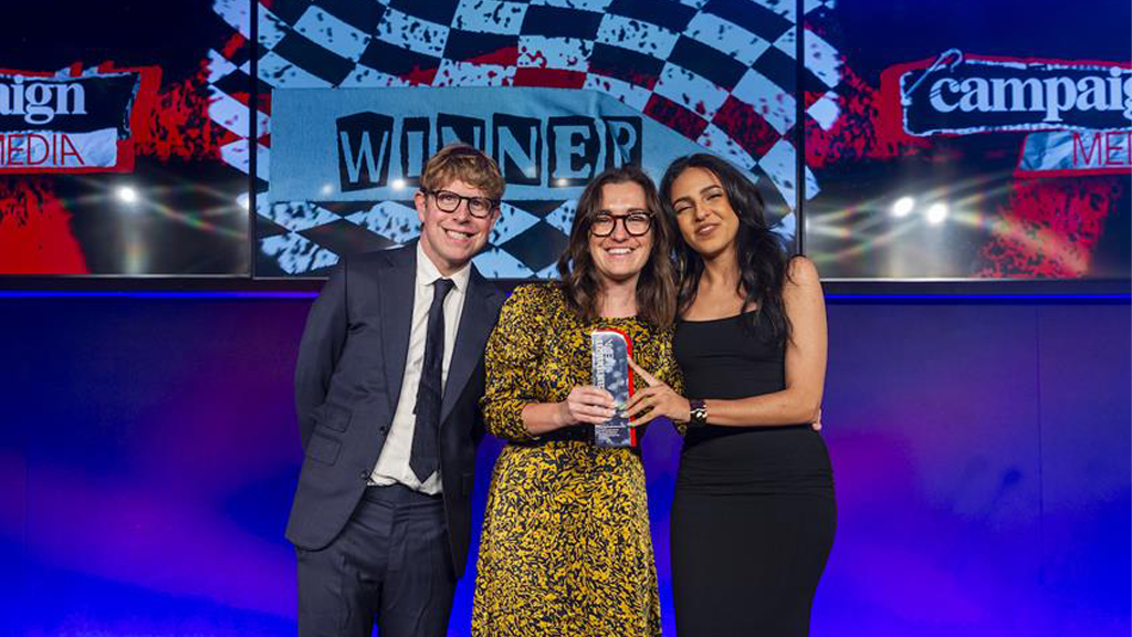 Josh Widdicombe poses with Lucie and Manal from Flourish holding the award.